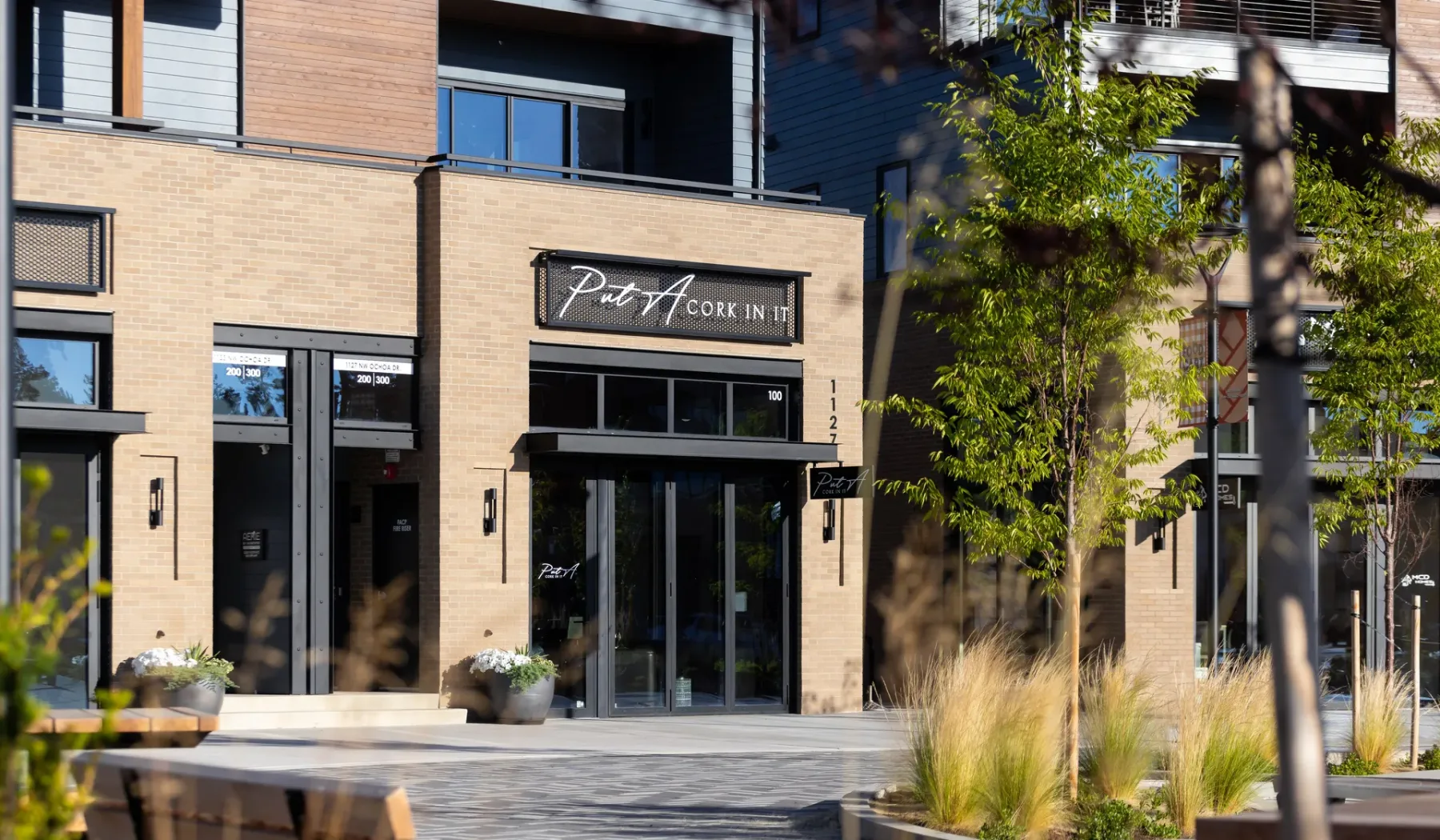A modern building entrance with large glass doors and landscaped planting.