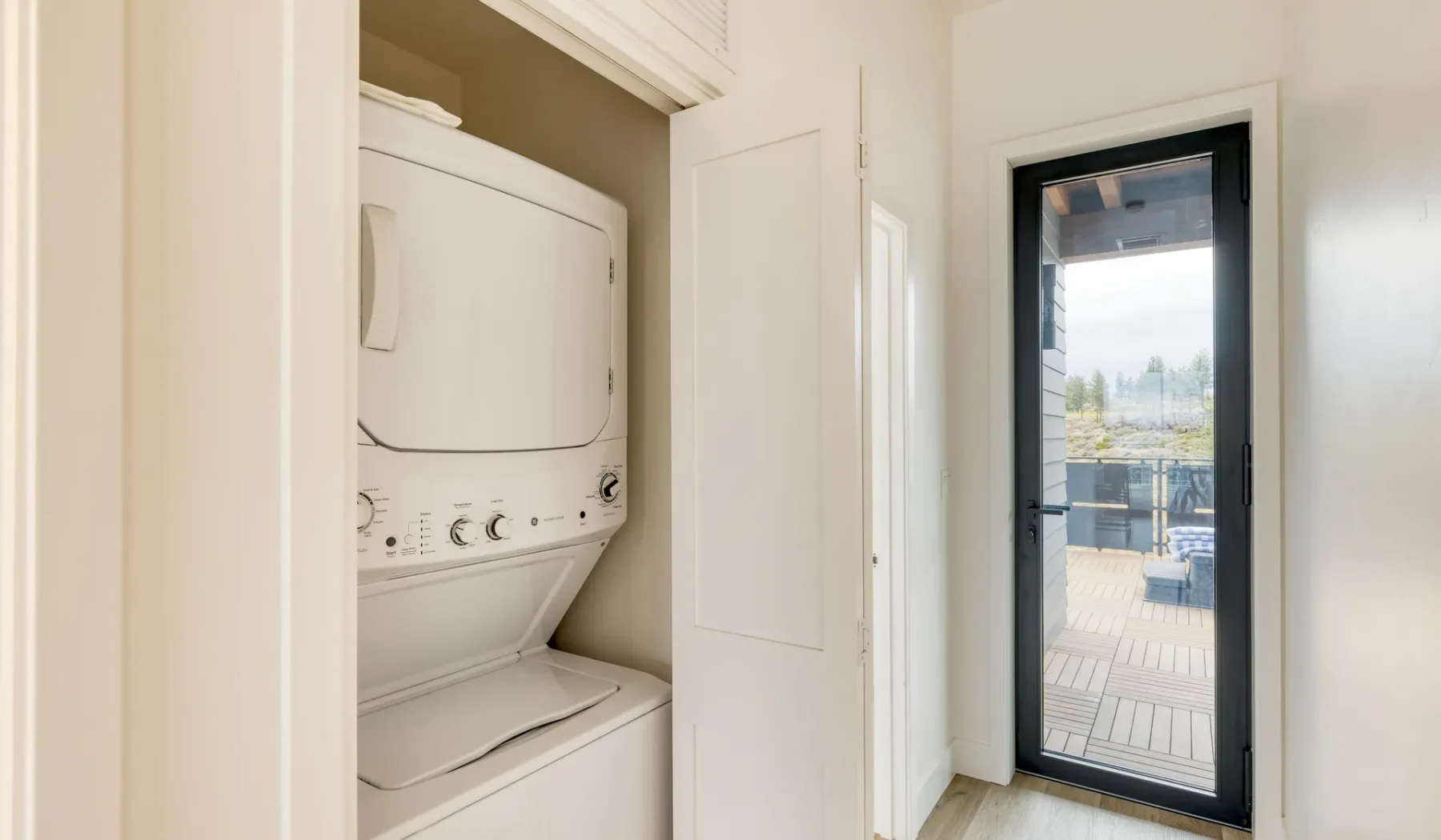 A laundry area with a stacked washer and dryer beside a glass patio door.