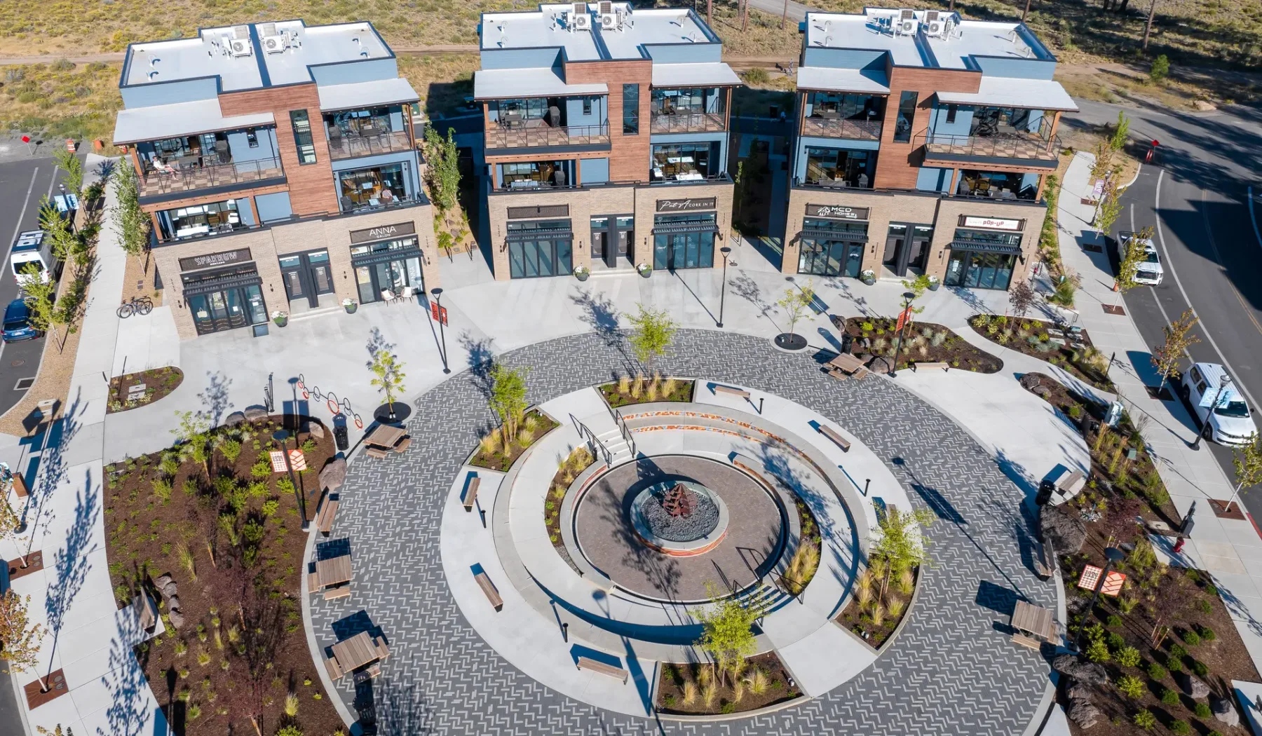 Aerial view of modern brick buildings surrounding a circular paved plaza with landscaped areas.