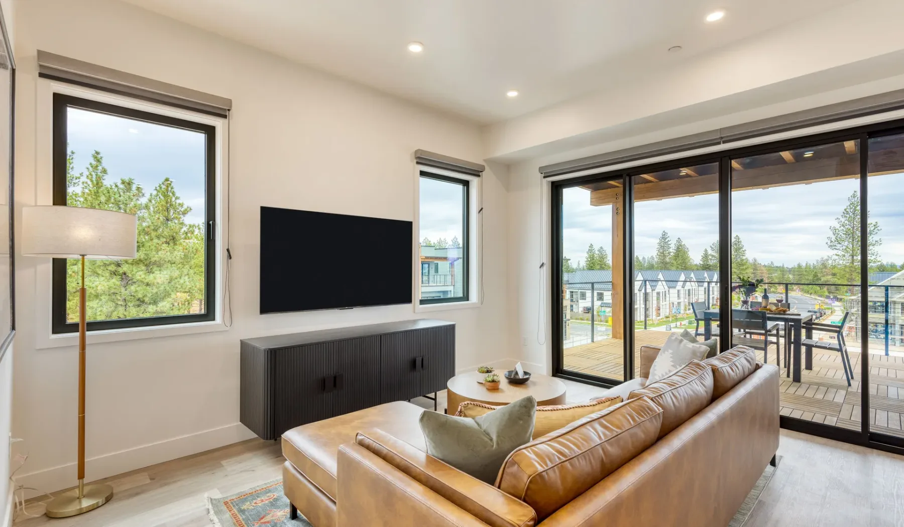 A bright living room with seating, a television, and sliding glass doors.