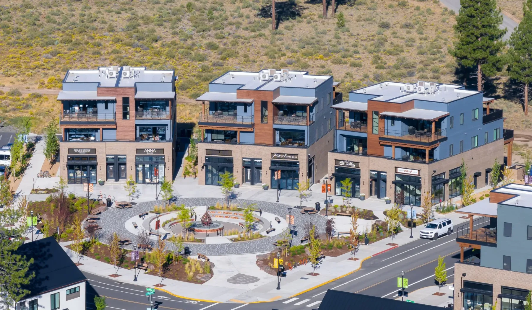 Aerial view of modern commercial buildings around a landscaped pedestrian plaza.