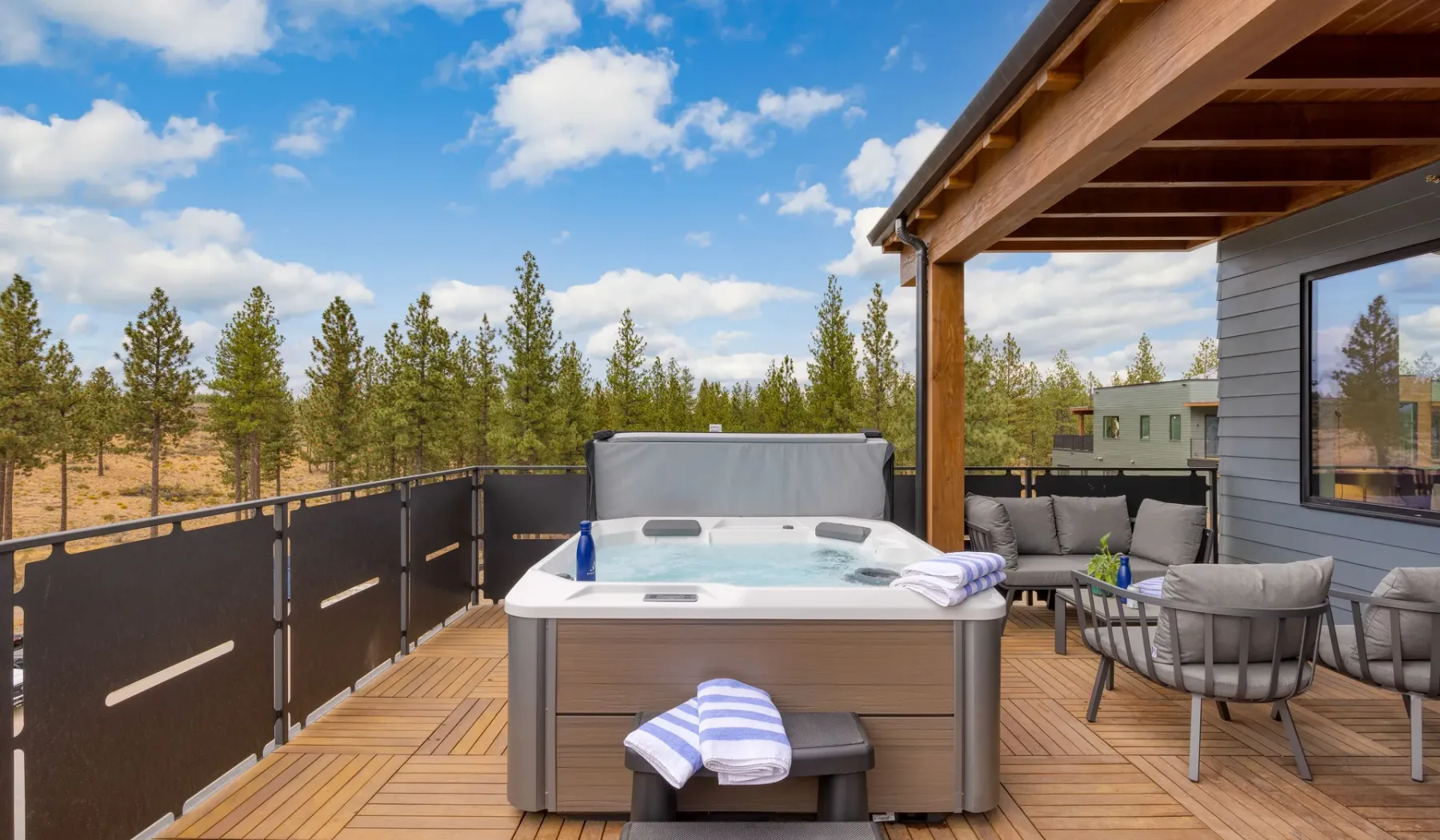 A rooftop deck features a hot tub and outdoor seating beneath a wooden pergola.