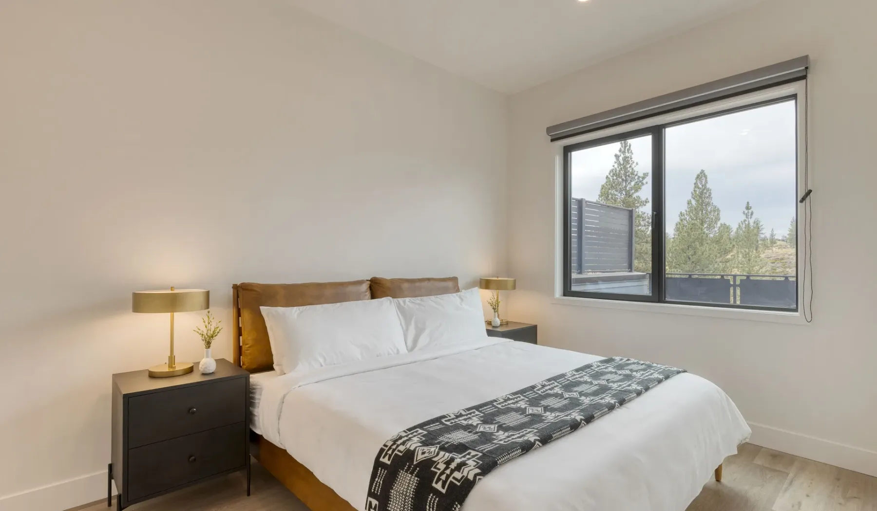 A bright bedroom with a neatly made bed and a large window.