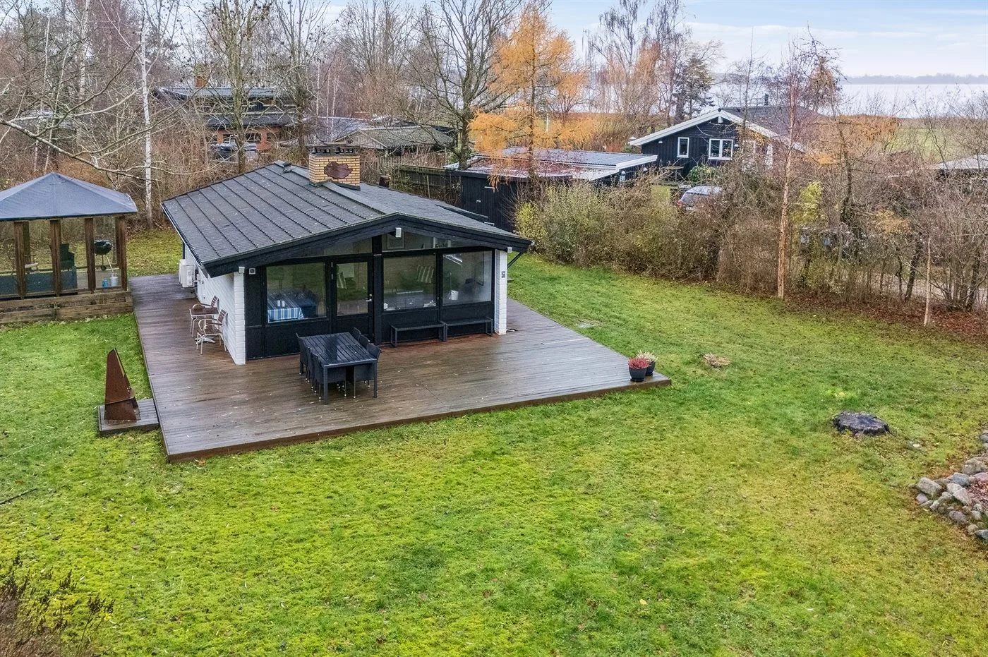 Aerial view of a modern house with a wooden deck and grassy yard.