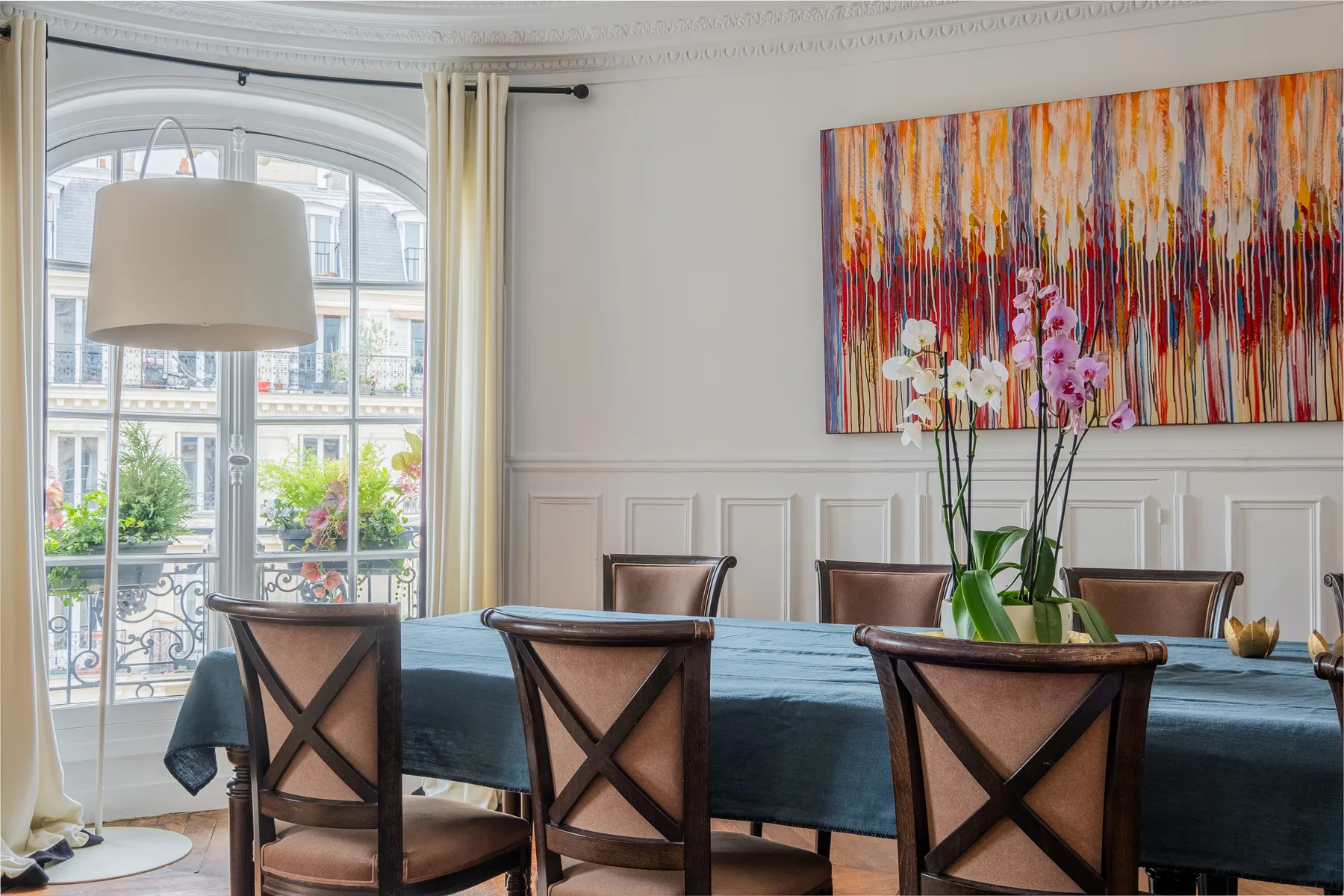 A dining room with a long table, wooden seating, and colorful wall art.