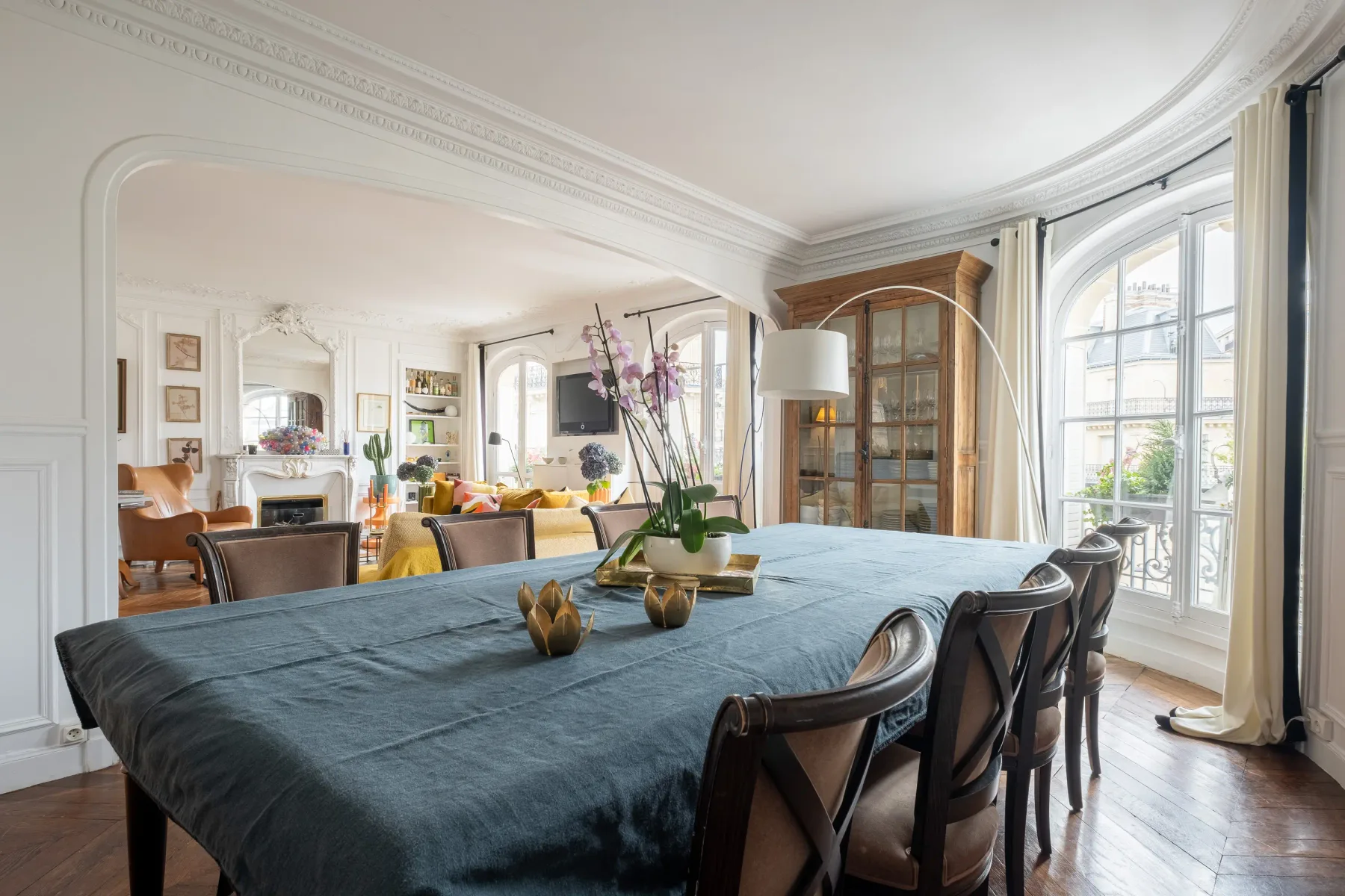 A dining room with a long table set beneath tall windows.