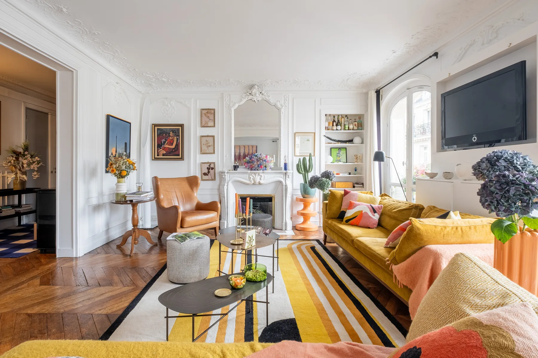 A bright living room with colorful seating and a fireplace.