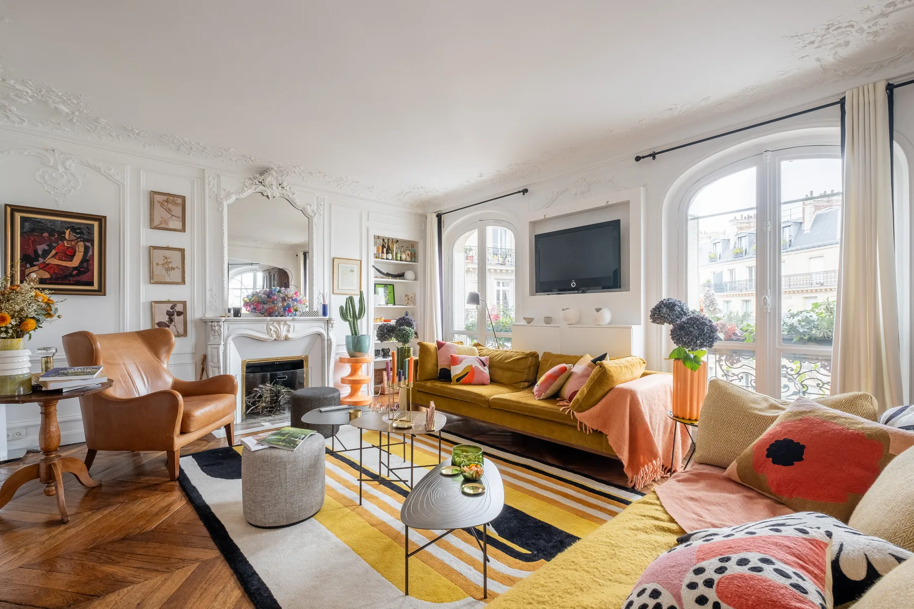 A bright living room with seating, a fireplace, and a wall-mounted television.