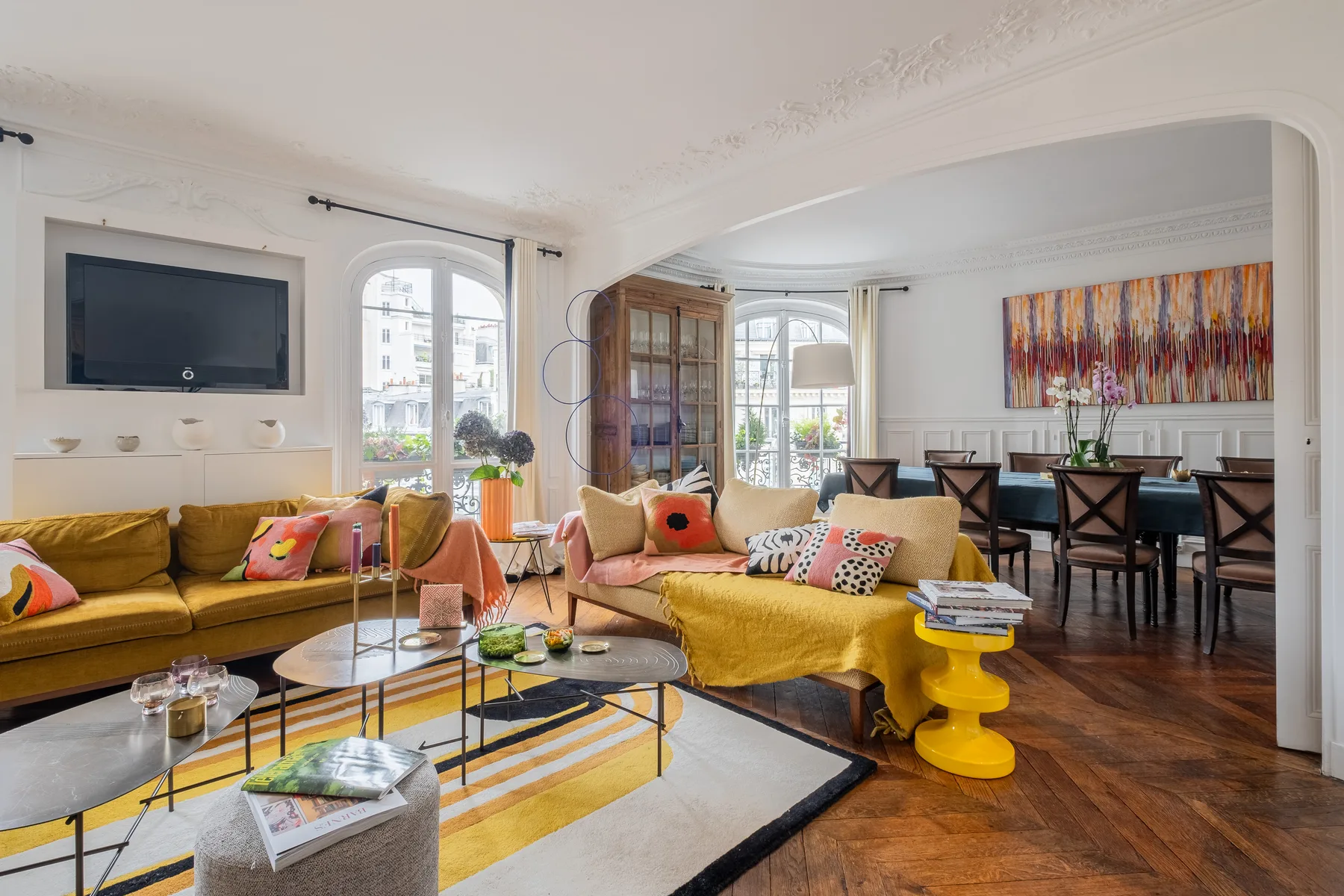 A bright living room with seating, a coffee table, and a dining area beyond.