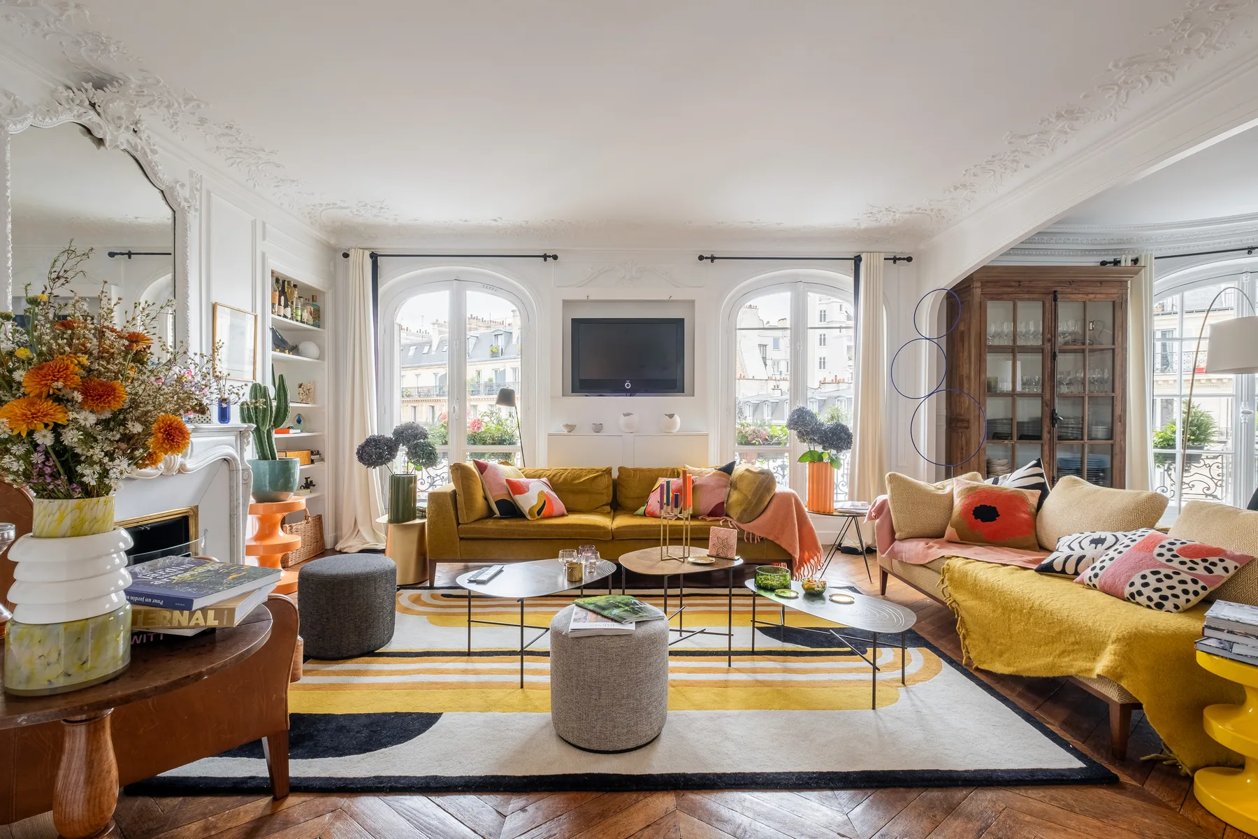 A bright living room with seating arranged around a low coffee table and wall-mounted television.