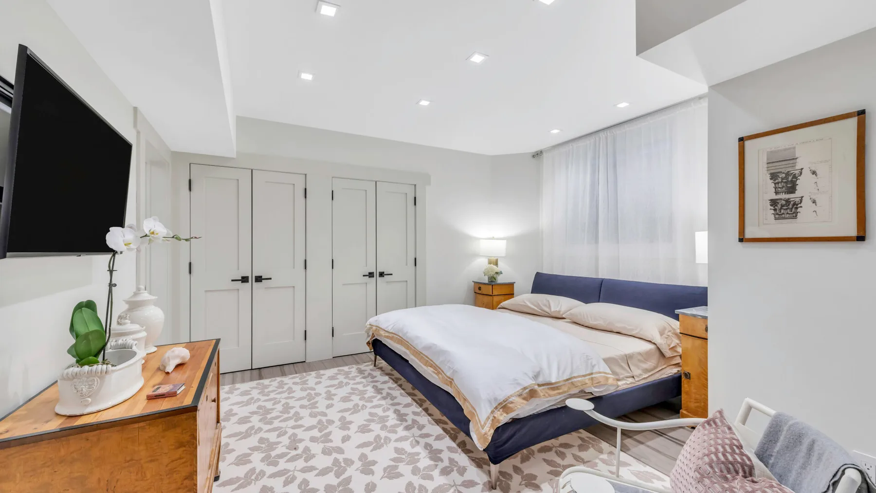 Un dormitorio luminoso con una cama grande, cortinas claras y armarios empotrados.