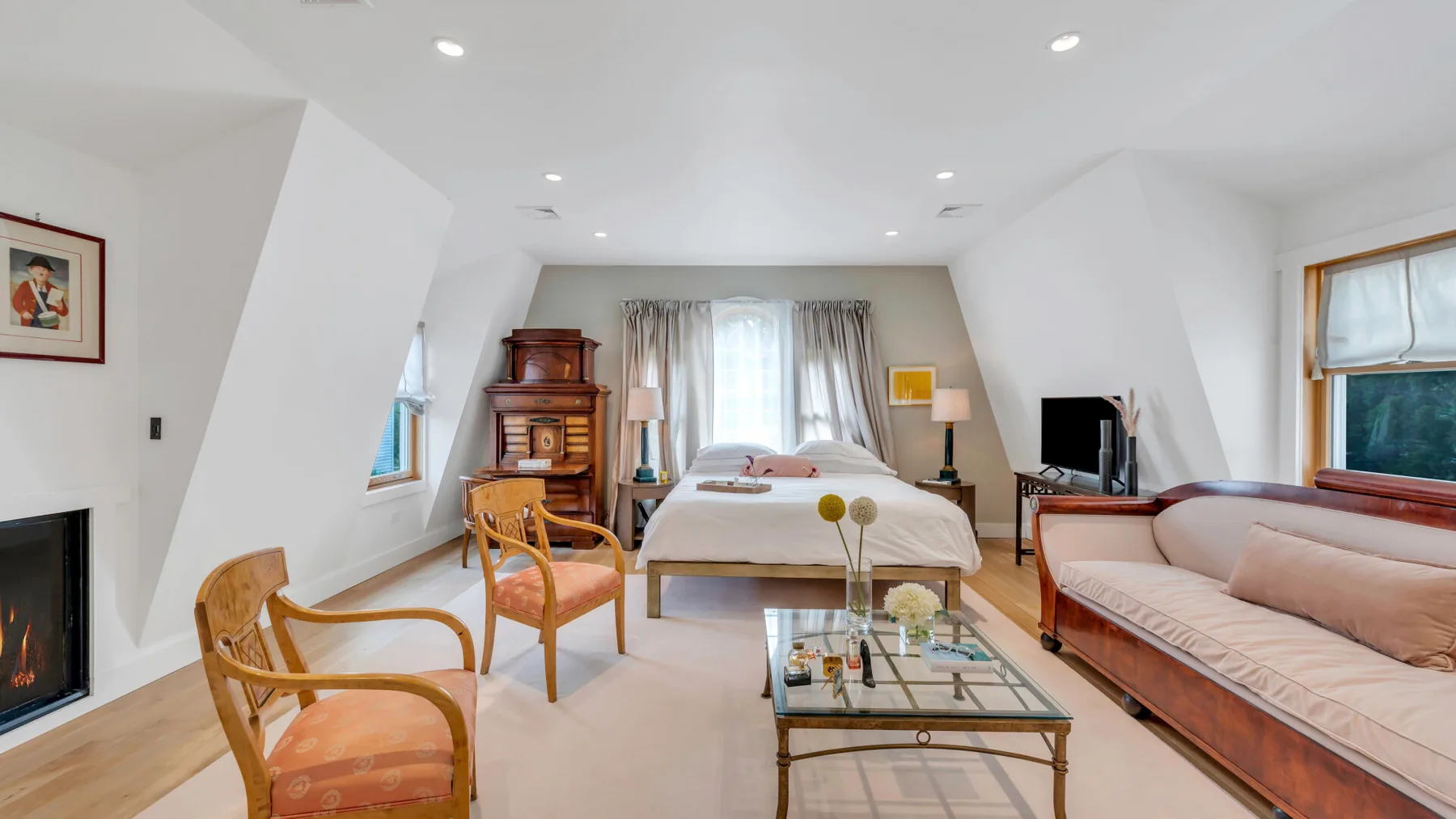 Un dormitorio luminoso con cama, zona de estar y televisor.