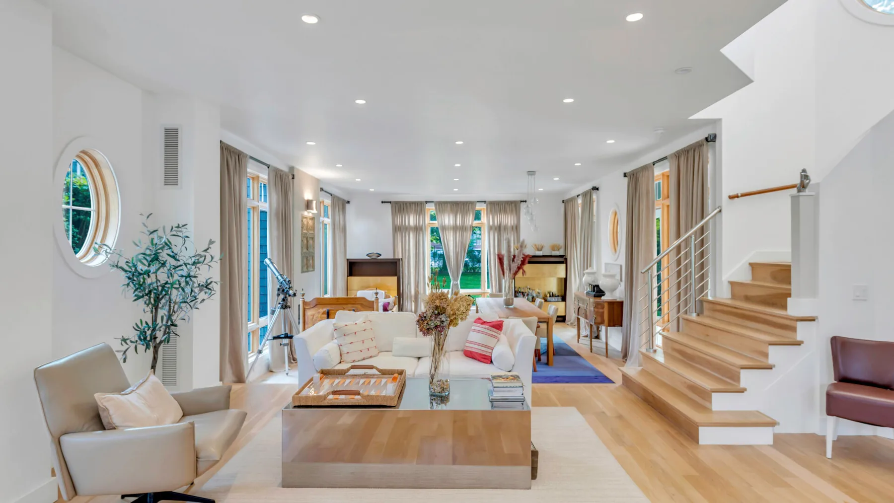 Una sala luminosa con asientos, una mesa de centro y una escalera.