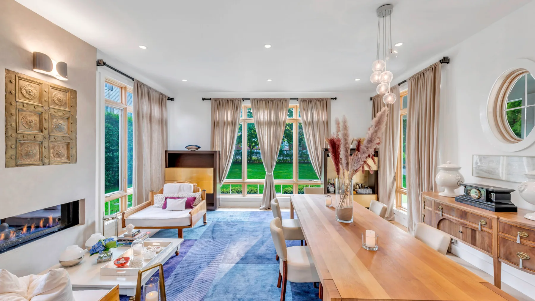 Un luminoso salón-comedor con grandes ventanas y una larga mesa de madera.