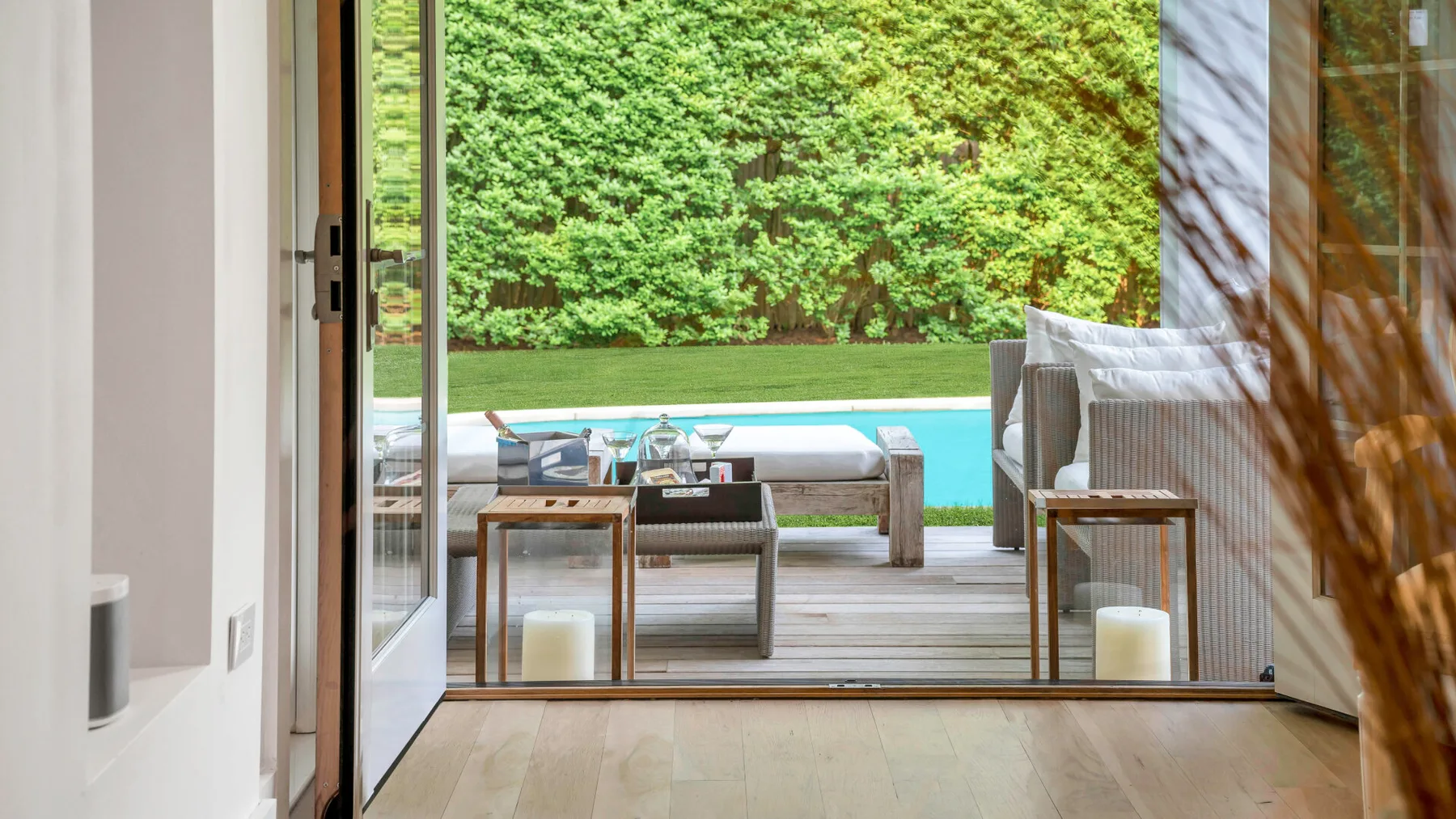 Una habitación luminosa se abre a un patio con asientos y una piscina.