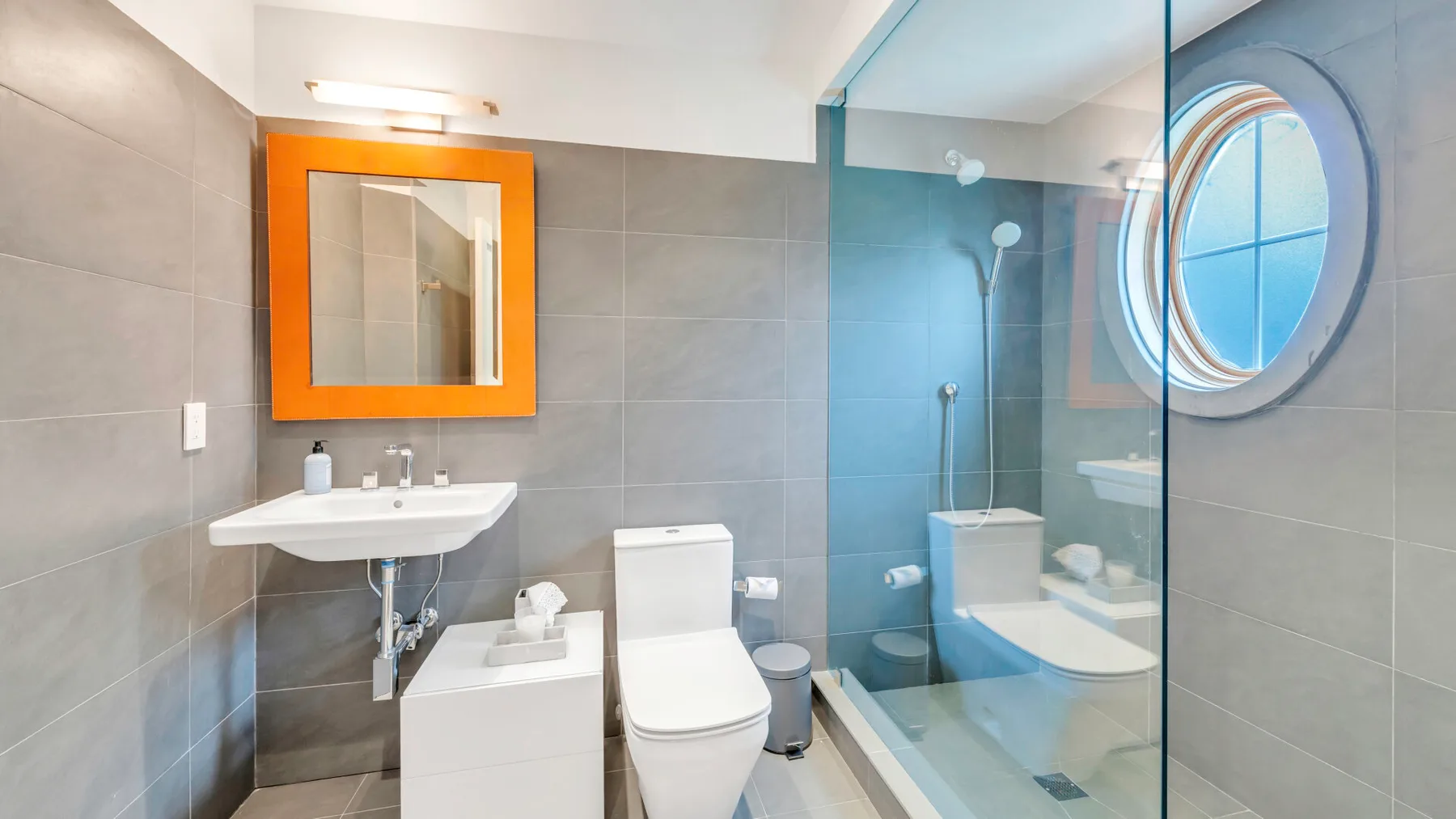 Un baño moderno con lavabo, inodoro y ducha con mampara de vidrio.