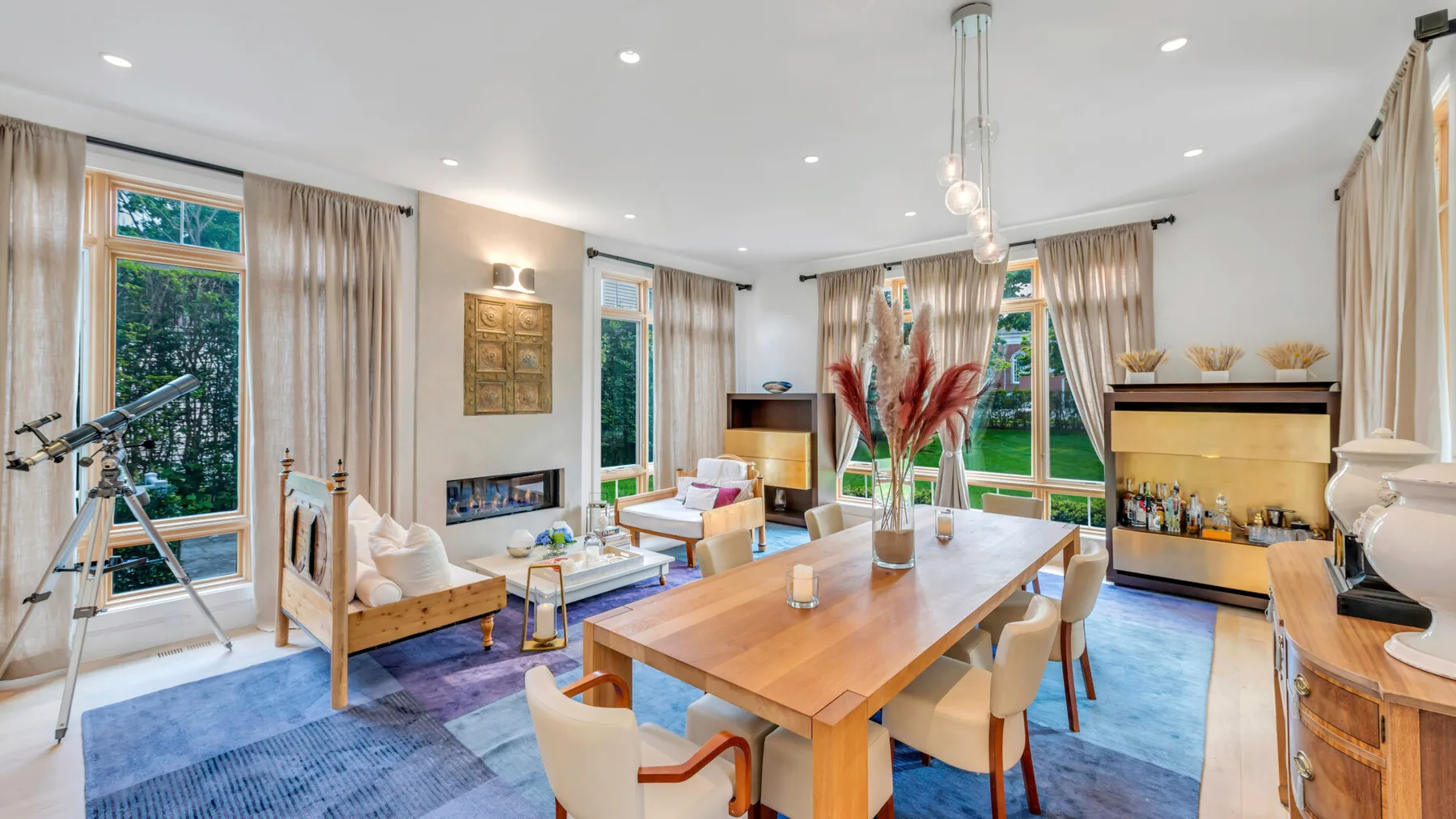 Una sala luminosa con mesa de comedor, asientos y grandes ventanas.