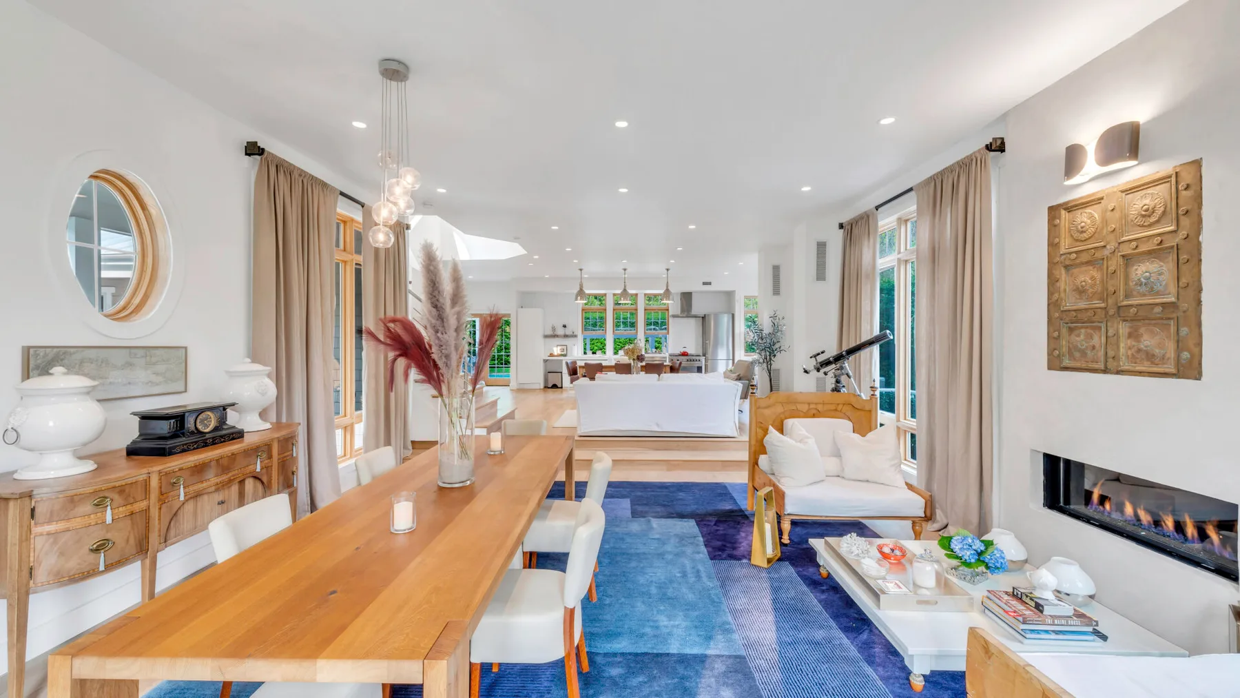 Una luminosa sala y comedor con una mesa larga de madera y una alfombra azul.
