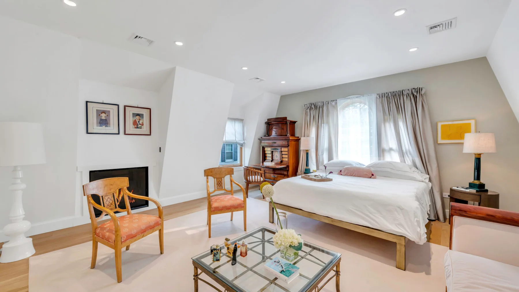 Un dormitorio luminoso con una cama, sillones y una mesa de centro de vidrio.