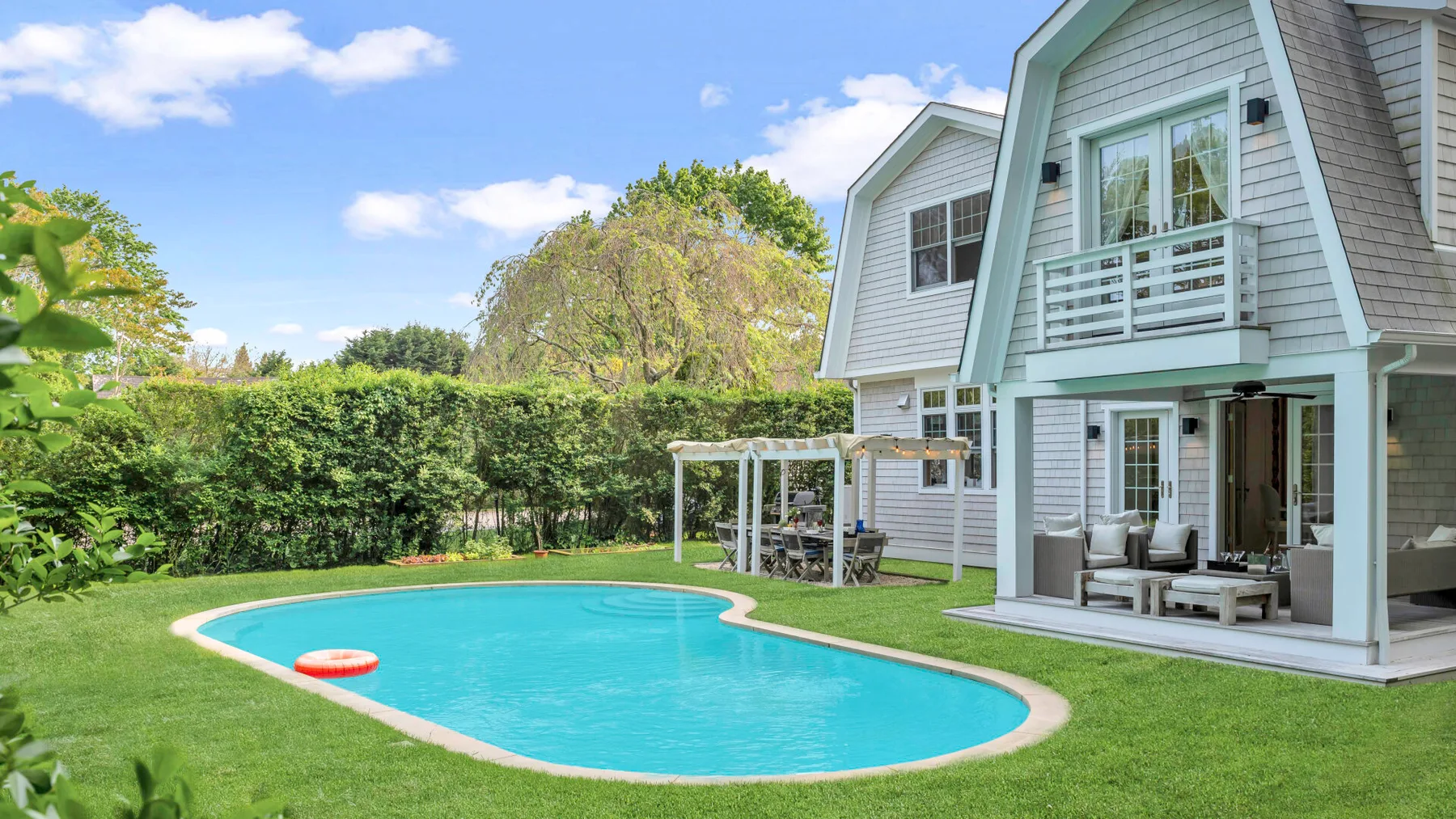 Una casa con una piscina curva y un patio cubierto.