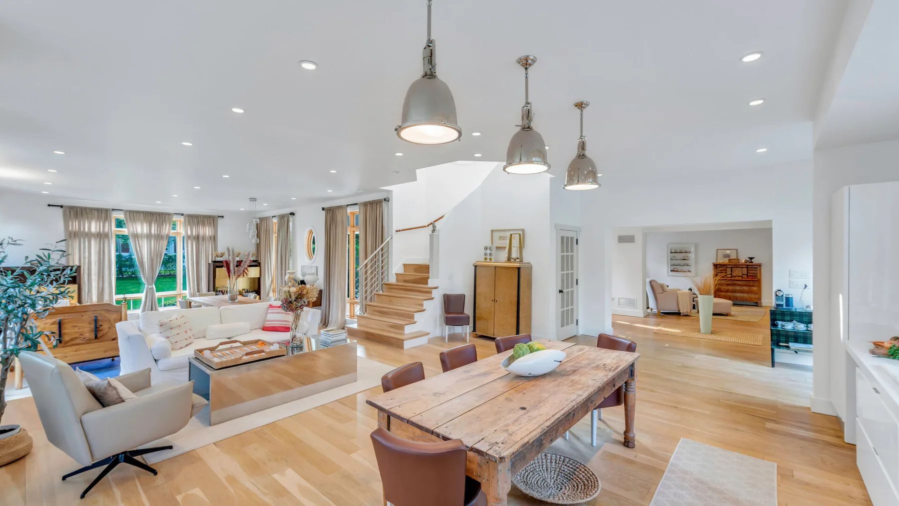 Una sala de estar y comedor de planta abierta con una mesa larga de madera y asientos.