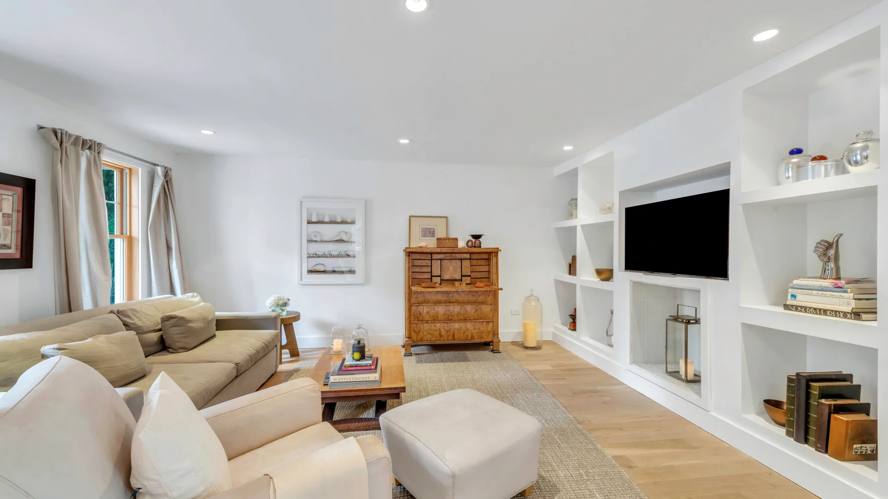 Una sala luminosa con asientos, un televisor y estantes empotrados.