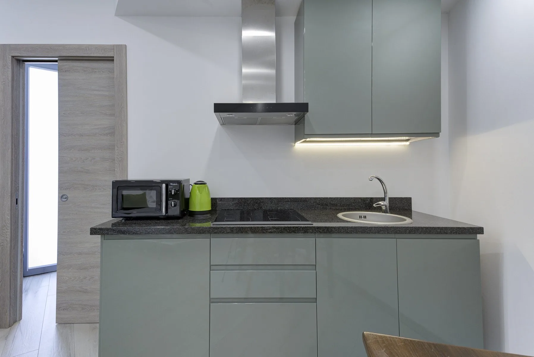 Una cocina moderna con gabinetes grises, una encimera oscura y un fregadero.