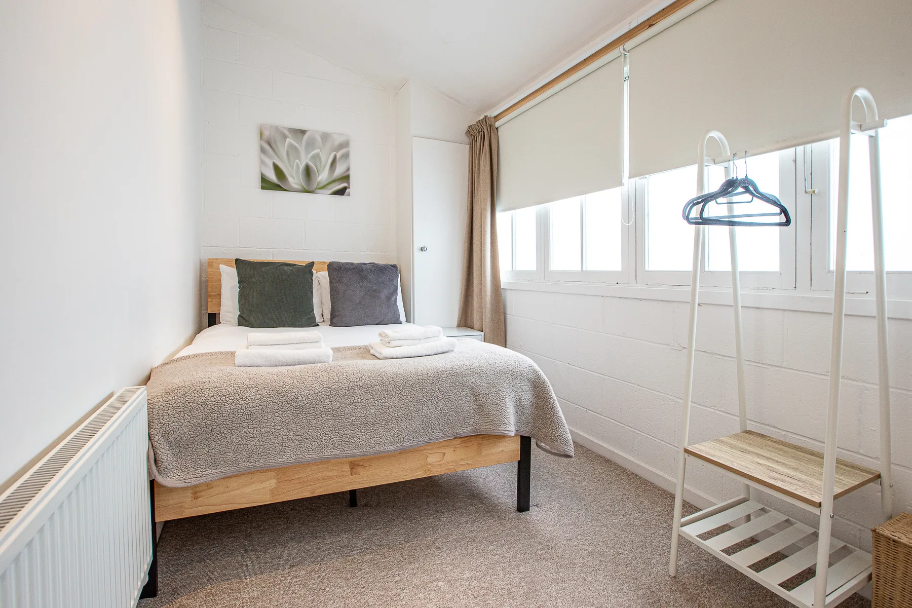 A bedroom with a neatly made bed beside a row of windows.