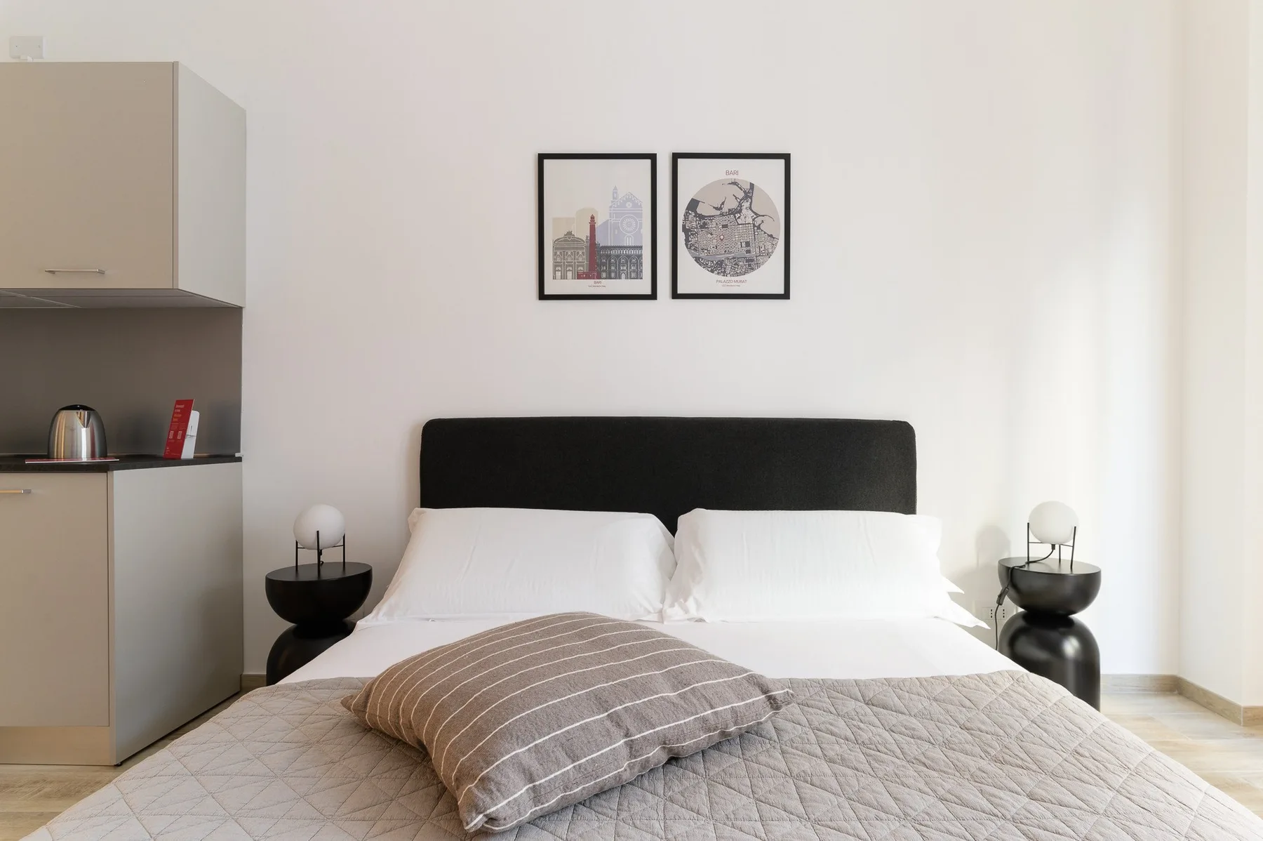 Un dormitorio con una cama doble, mesitas de noche y cuadros sobre el cabecero.