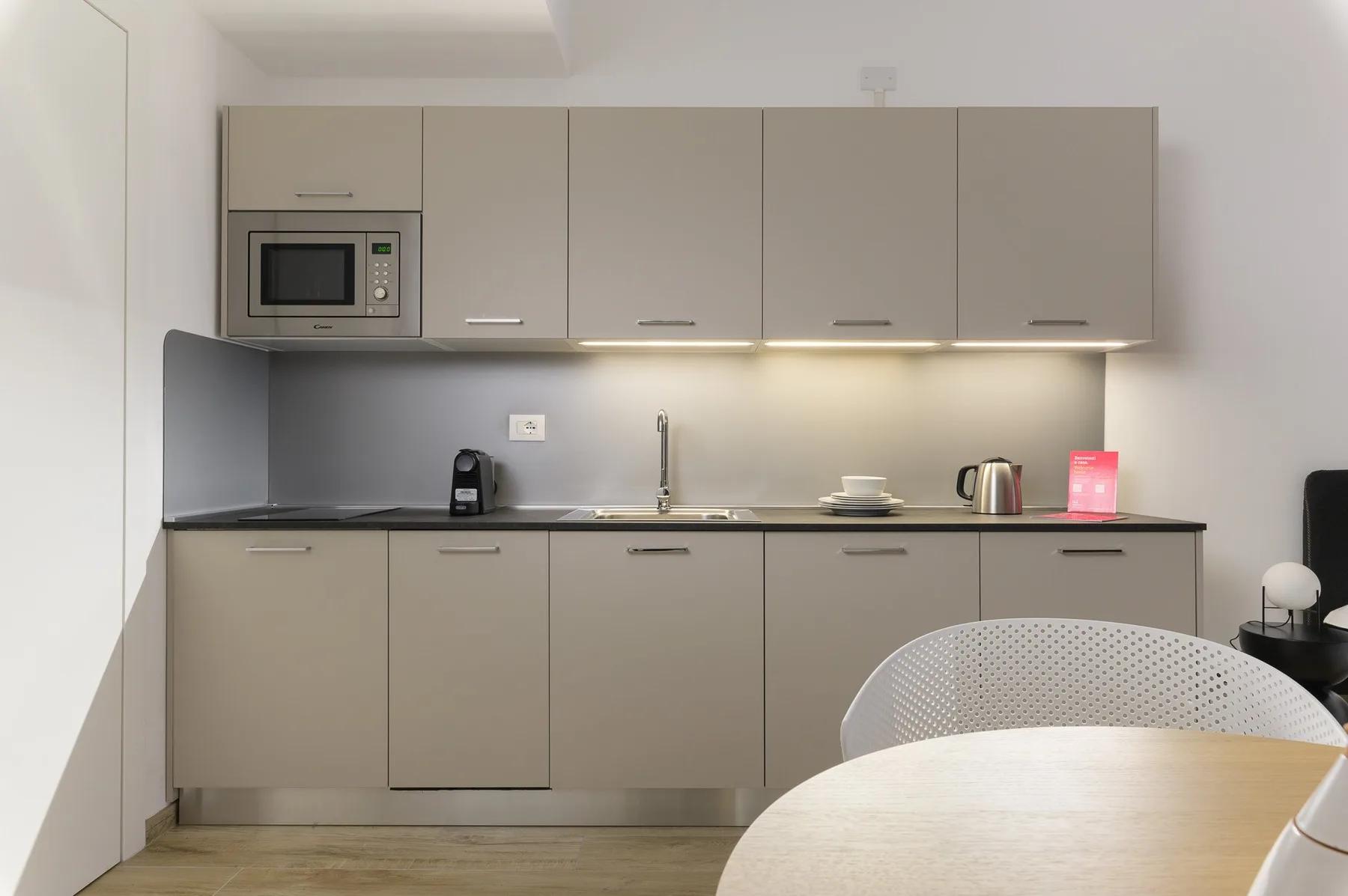 A modern kitchen with gray cabinets, a countertop, and a microwave.