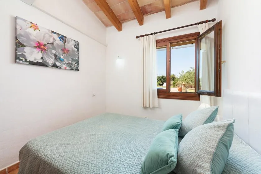 A bedroom with a neatly made bed and an open window.