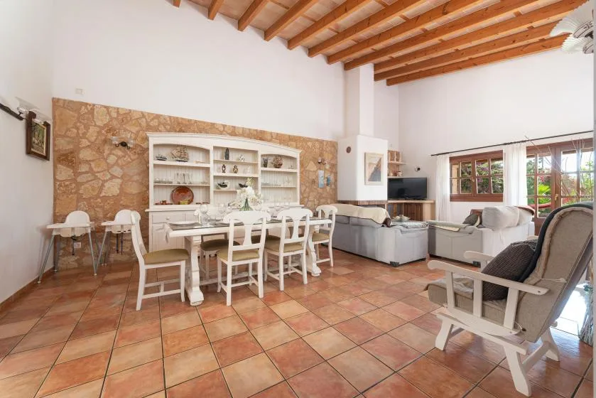 A spacious living and dining room with a table, seating, and exposed ceiling beams.