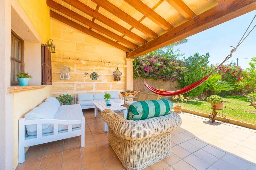 A covered outdoor seating area opens onto a garden, with a hammock hanging nearby.