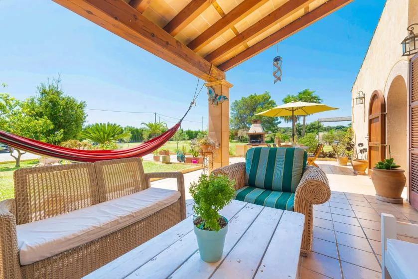 A covered outdoor patio with seating, a hammock, and a table.