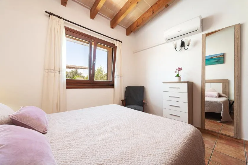 A bedroom with a bed, a window, and a chest of drawers.