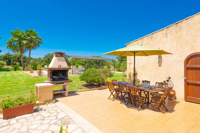 An outdoor patio with a dining table and a built-in barbecue.