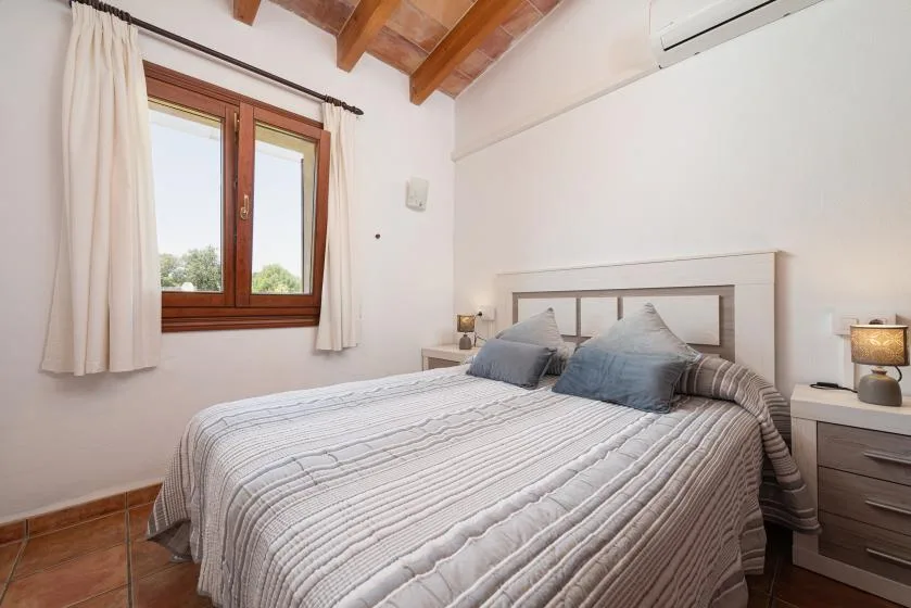 A bedroom with a double bed beneath a wood-beamed ceiling.