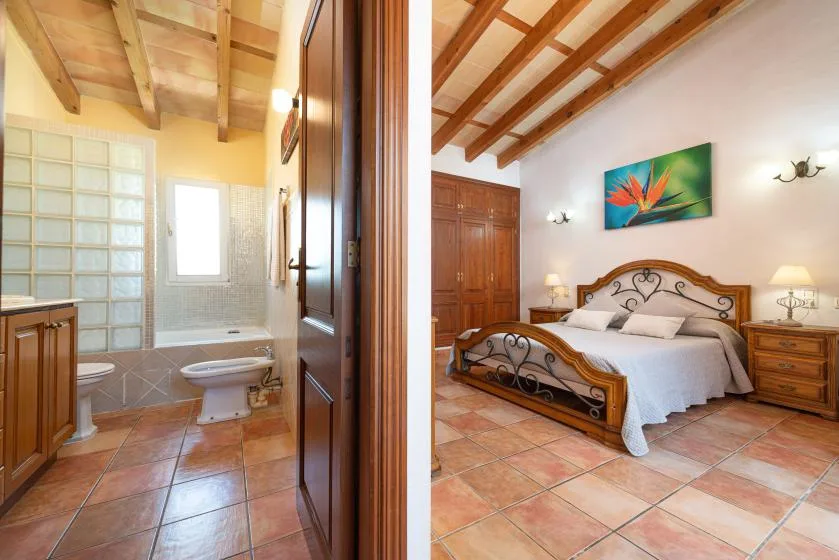 A bedroom with a metal-framed bed beside an adjoining bathroom.