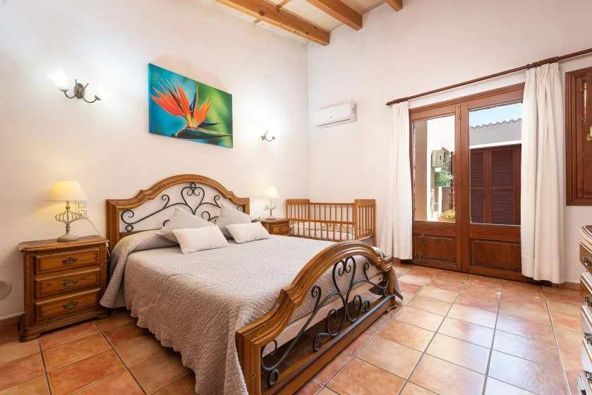 A bedroom with a large bed, wooden furniture, and glass doors opening onto a balcony.