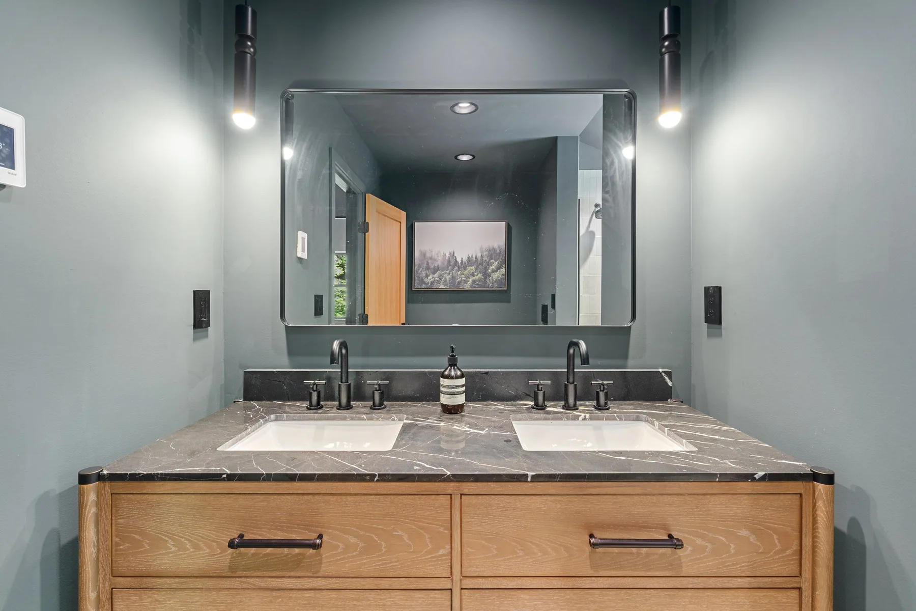 A bathroom vanity with two sinks sits beneath a large wall mirror.