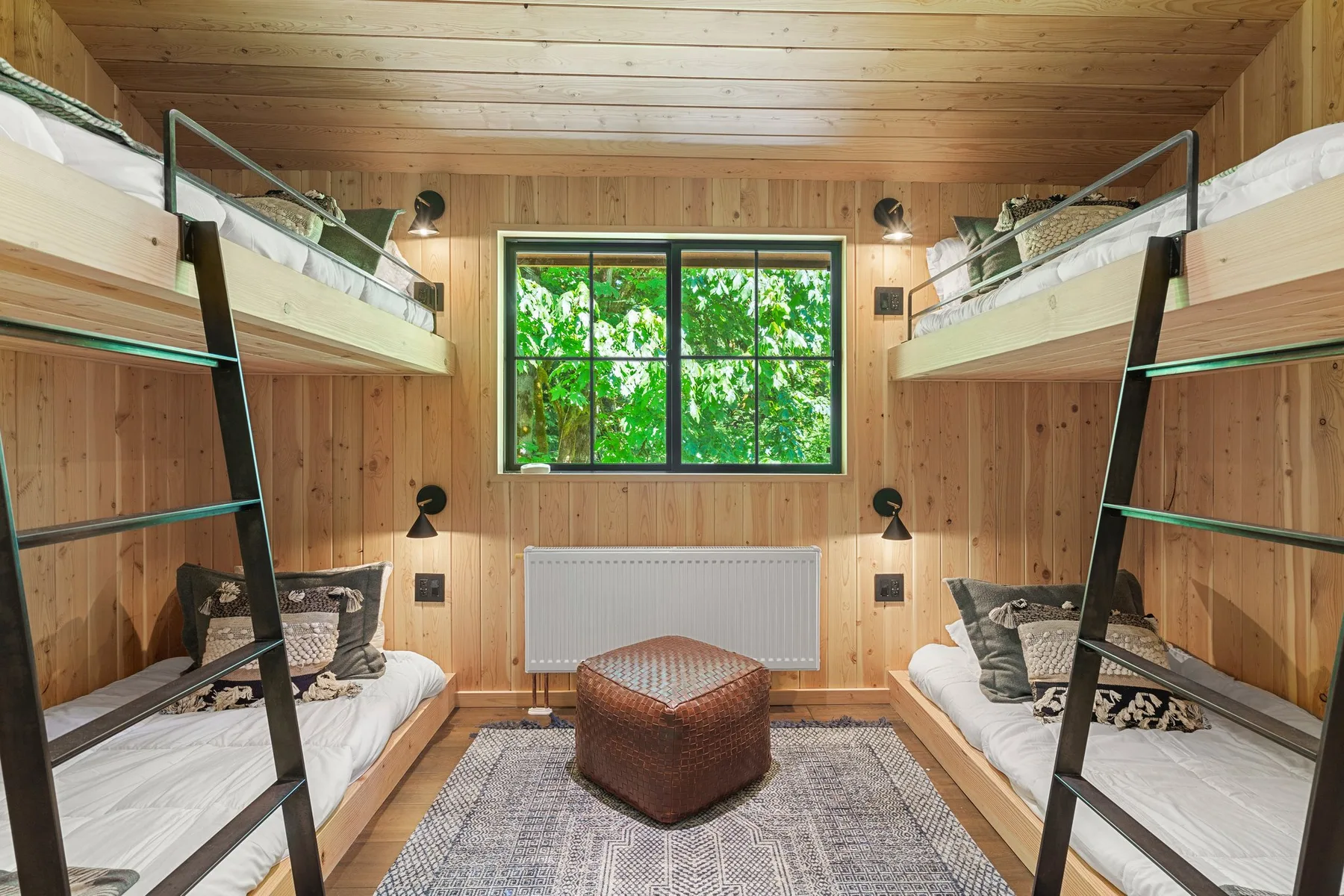A wood-paneled bedroom with bunk beds, a central window, and a rug.