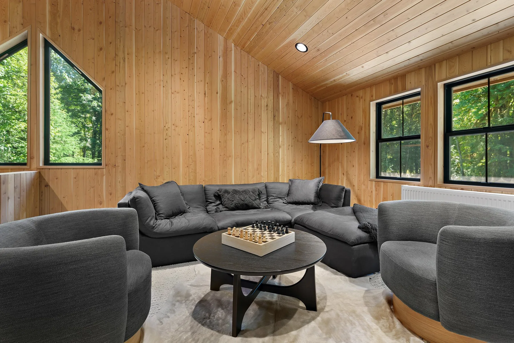 A wood-paneled living room with gray seating around a coffee table.