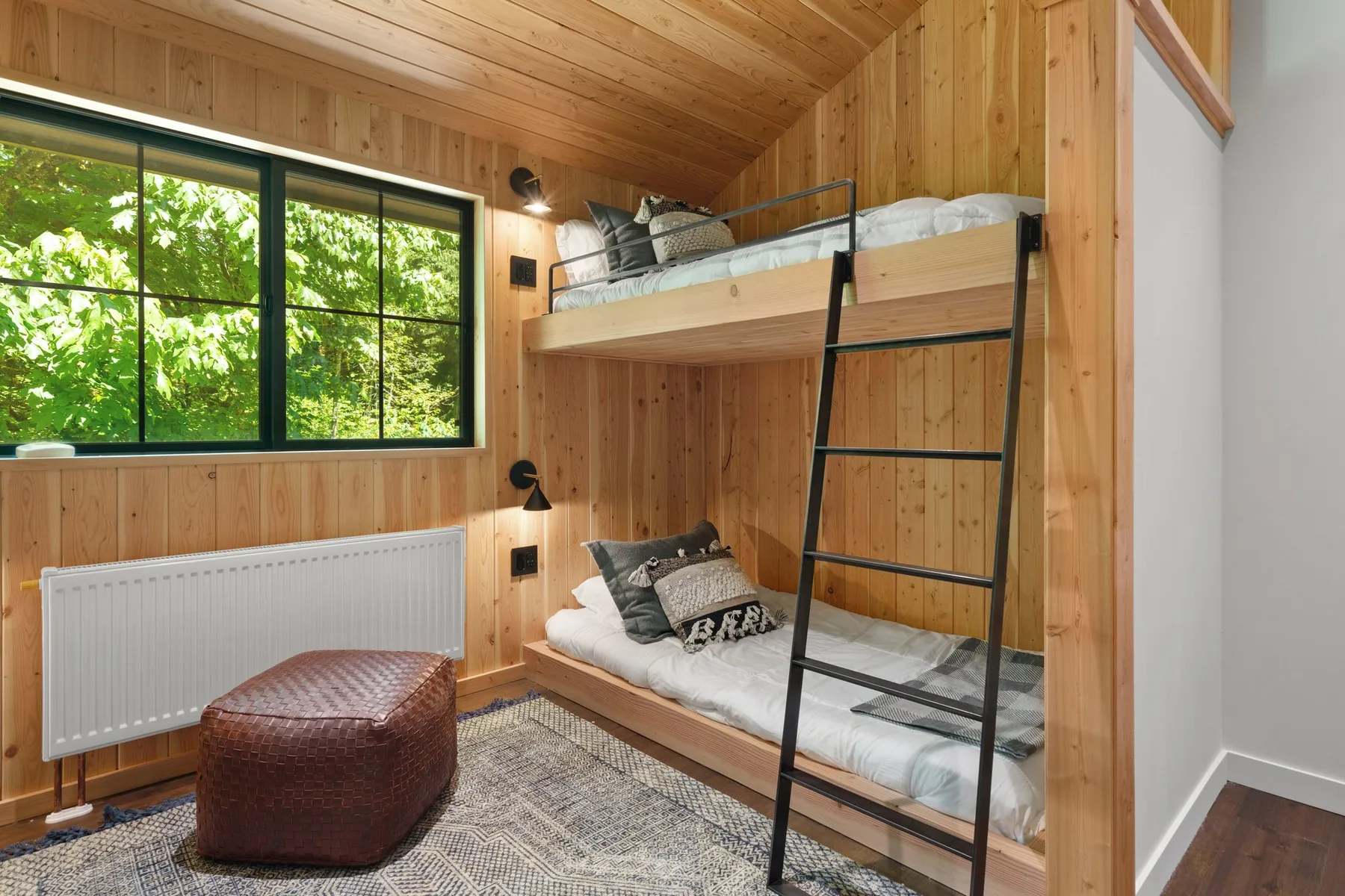 A wood-paneled bedroom has bunk beds beside a large window.