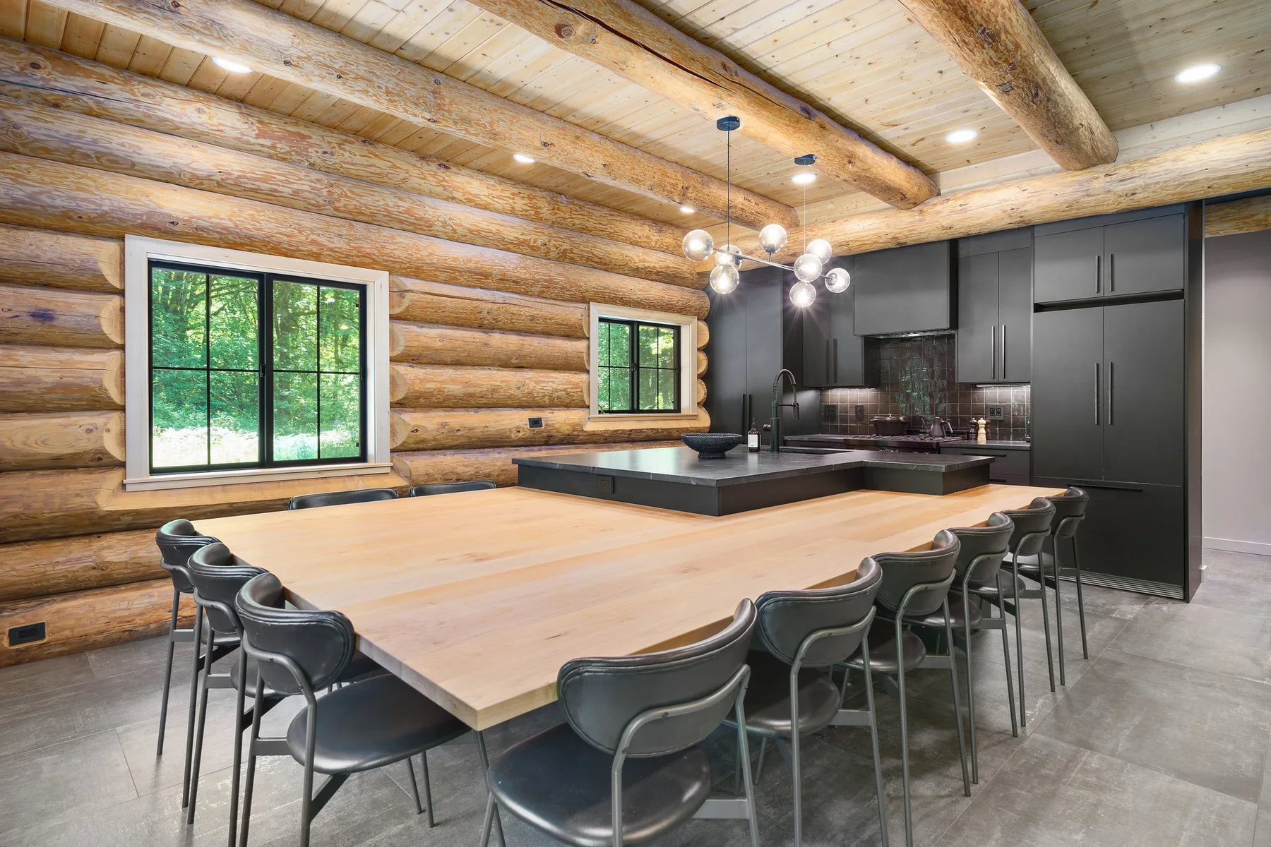A rustic kitchen and dining area with a large island and dark cabinetry.