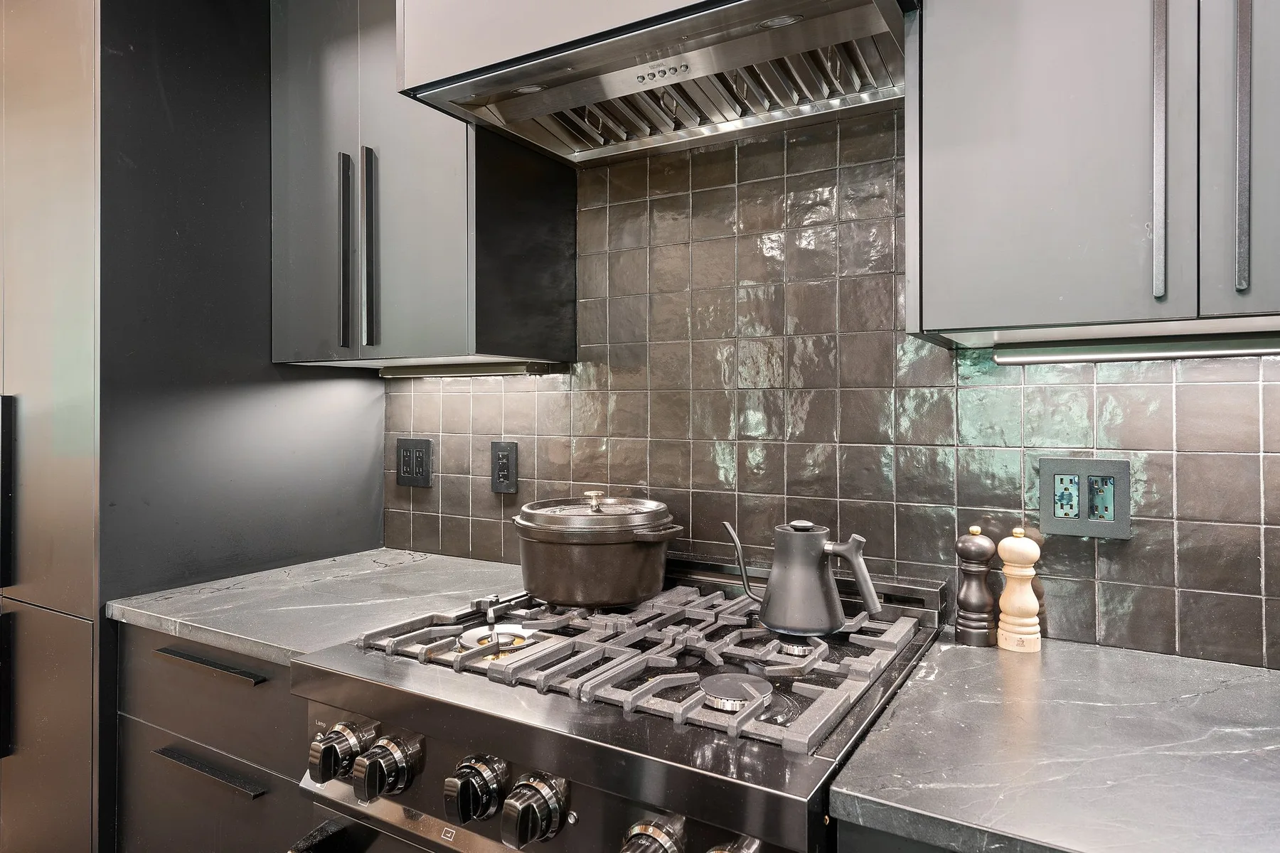 A modern kitchen with a stainless-steel gas cooktop beneath a range hood.