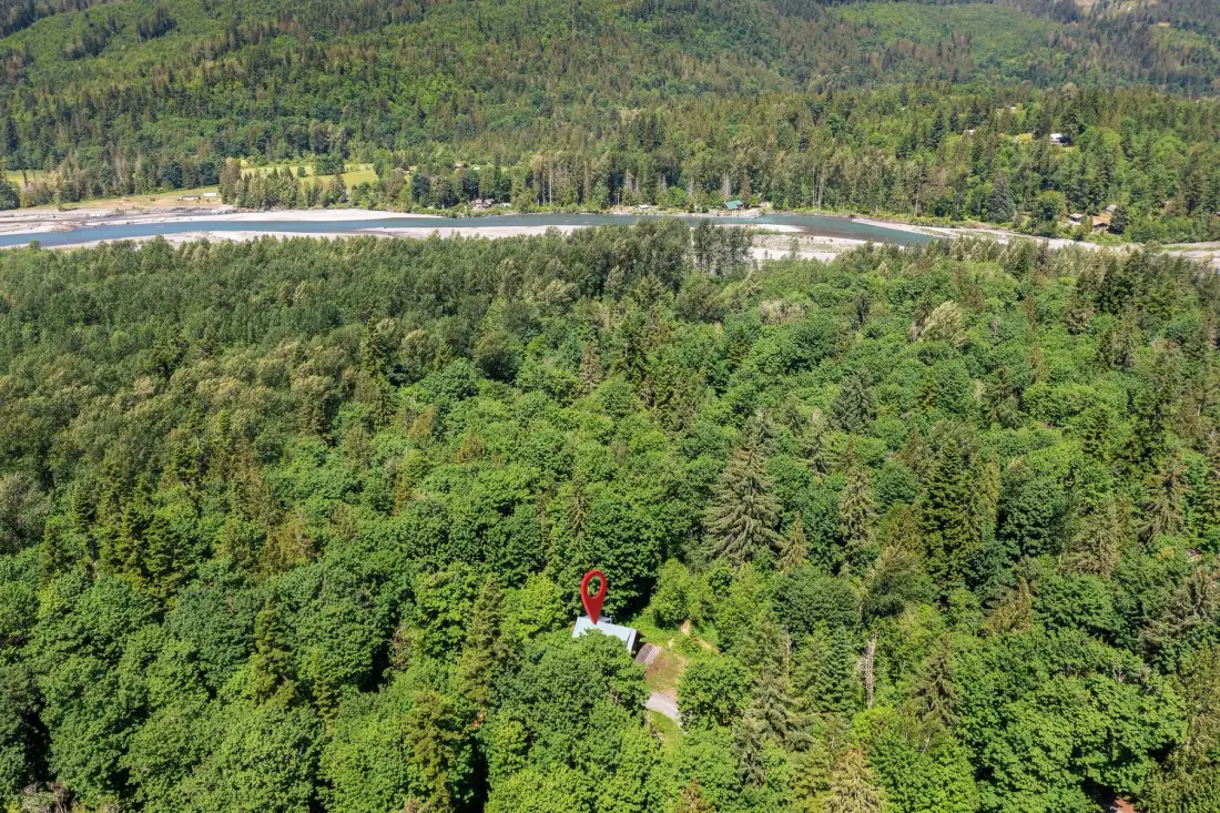 Aerial view of dense forest surrounding a small building.