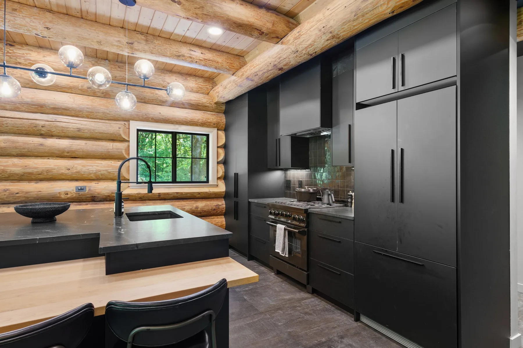 A modern kitchen with dark cabinets, a large island, and a log-style wood ceiling.