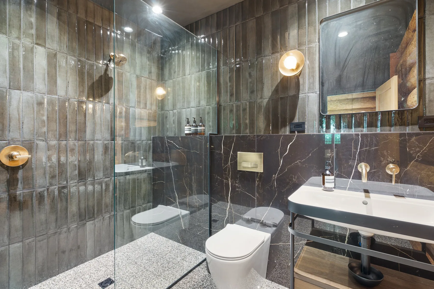 A modern bathroom with a glass shower, toilet, and sink.