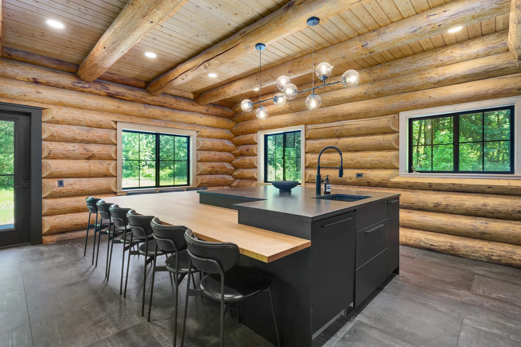 A log-cabin kitchen with a dark island and a row of seating.