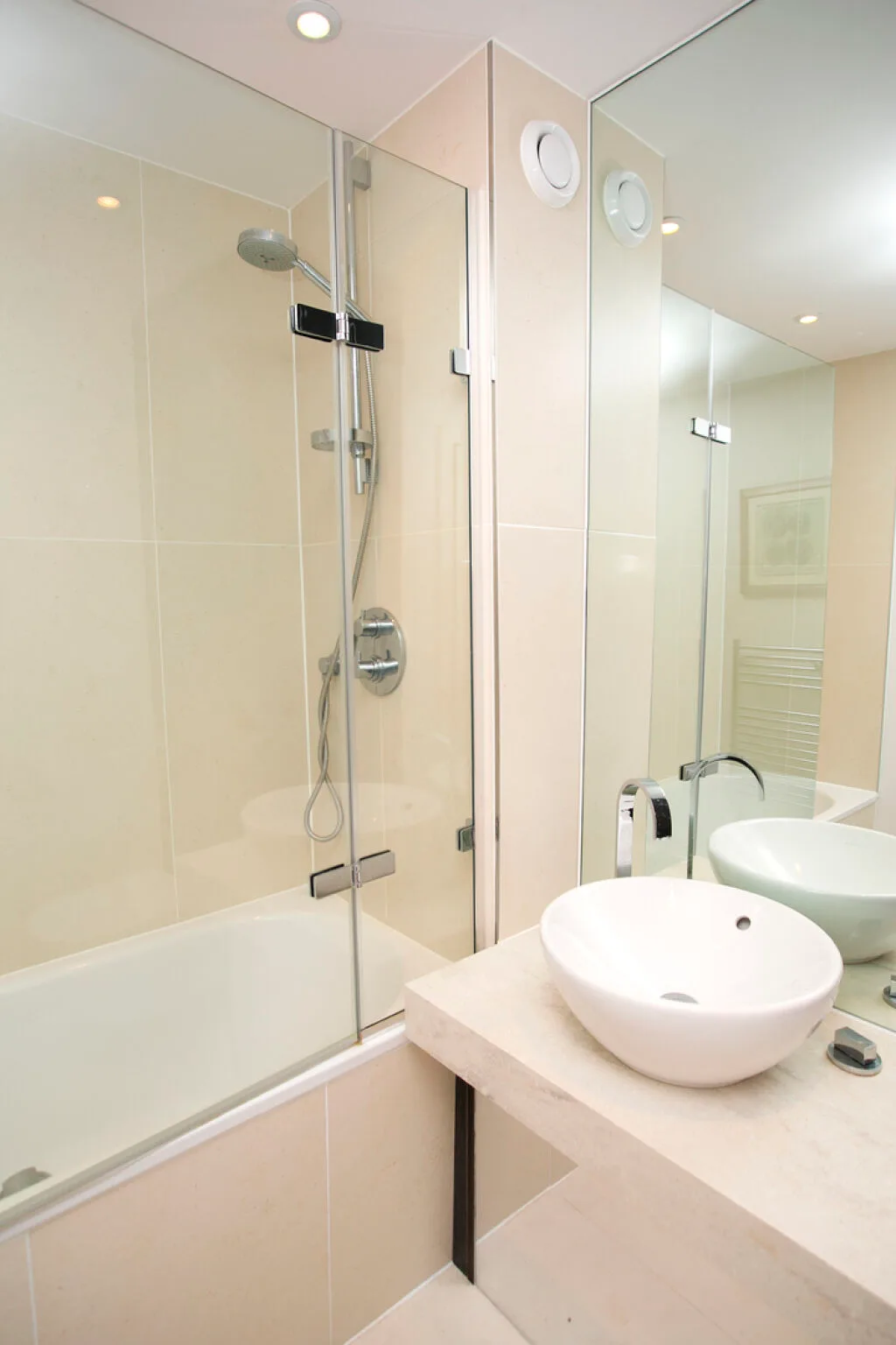 A bright bathroom with a glass-enclosed shower and a vessel sink.